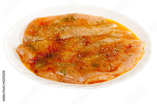 Photo: Raw marinated chicken breasts with spices isolated on white Raw marinated chicken breasts with spices isolated on white