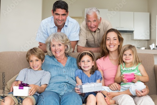 Photo: Siblings holding gifts with family in living room Siblings holding gifts with family in living room