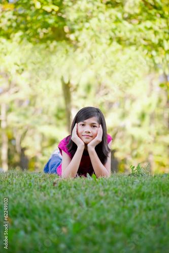 Photo: Little girl lying down on grass Little girl lying down on grass