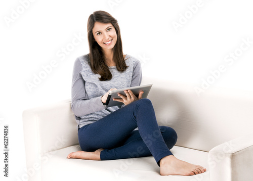 Photo: Beautiful woman sitting on the soda and working with a tablet Beautiful woman sitting on the soda and working with a tablet