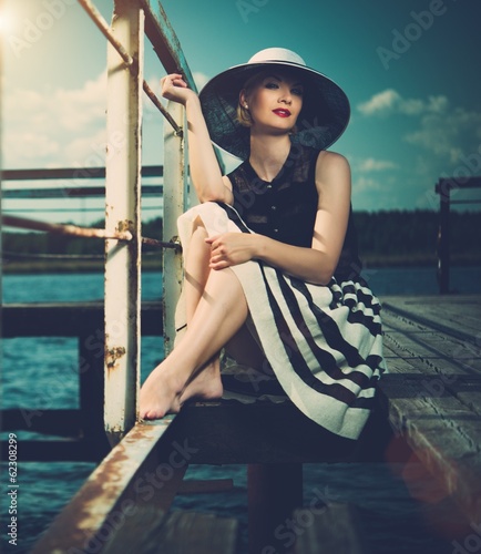 Photo: Beautiful woman sitting on old wooden pier Beautiful woman sitting on old wooden pier