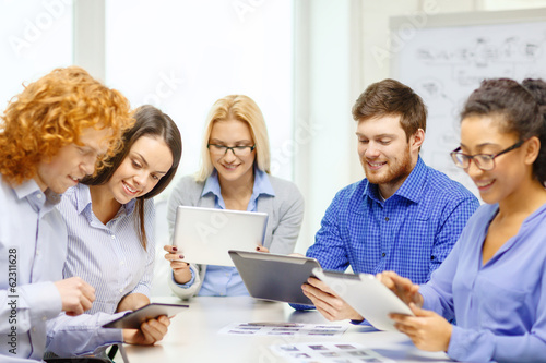 Photo: smiling team with table pc and papers working smiling team with table pc and papers working