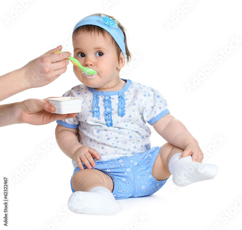 Photo: Cute baby girl eating isolated on white Cute baby girl eating isolated on white