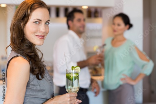 Photo: Smiling woman holding cocktail glass with friends in Smiling woman holding cocktail glass with friends in
