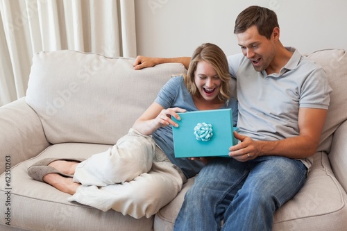 Photo: Shocked woman receiving a gift by man in living room Shocked woman receiving a gift by man in living room