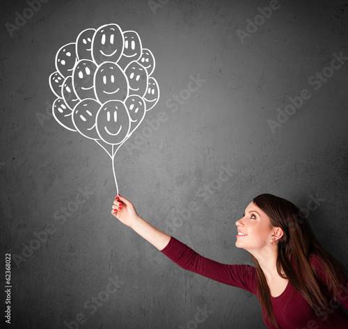 Photo: Woman holding a bunch of smiling balloons Woman holding a bunch of smiling balloons