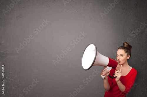Photo: Girl shouting into megaphone on copy space background Girl shouting into megaphone on copy space background