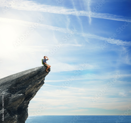 Photo: Young man sitting on a peak Young man sitting on a peak