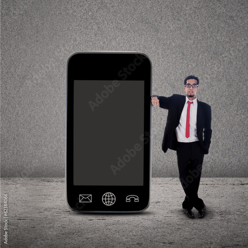 Photo: Businessman and smartphone on grey Businessman and smartphone on grey