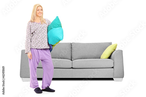 Photo: Blond woman in pajamas standing in front of a sofa Blond woman in pajamas standing in front of a sofa