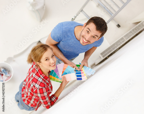 Photo: smiling couple looking at color samples at home smiling couple looking at color samples at home