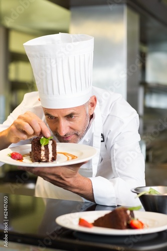 Photo: Concentrated male pastry chef decorating dessert in kitchen Concentrated male pastry chef decorating dessert in kitchen