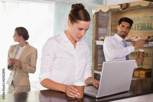 Photo: Businesswoman using laptop in office cafeteria Businesswoman using laptop in office cafeteria