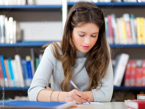 Photo: Female student studying in a library Female student studying in a library
