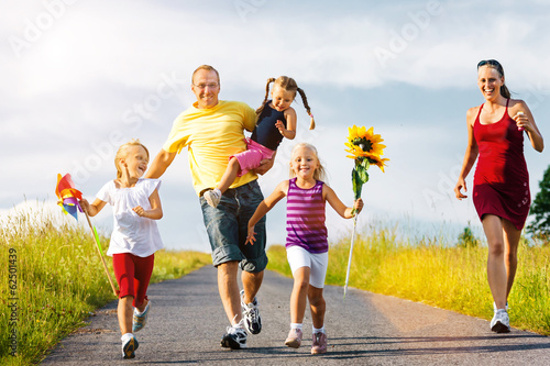 Photo: Familie läuft einen Hügel herunter Familie läuft einen Hügel herunter