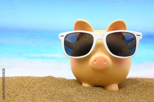 Photo: Summer piggy bank with sunglasses on the beach Summer piggy bank with sunglasses on the beach
