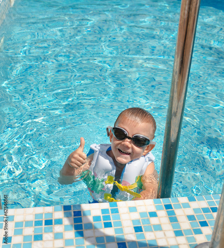 Photo: Happy goung boy in a swimming pool giving a thumbs up Happy goung boy in a swimming pool giving a thumbs up