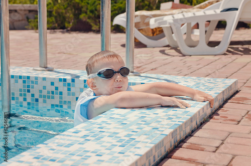 Photo: Small boy clambering out of a swimming pool Small boy clambering out of a swimming pool