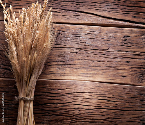 Photo: Ears of wheat on old wooden table. Ears of wheat on old wooden table.