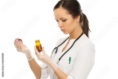 Photo: Young doctor woman reading prescription on a vial Young doctor woman reading prescription on a vial