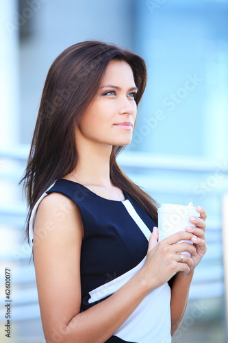 Photo: smiling young smart businesswoman having coffee break in office smiling young smart businesswoman having coffee break in office