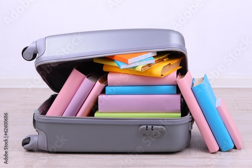 Photo: Books in suitcase on wall background Books in suitcase on wall background