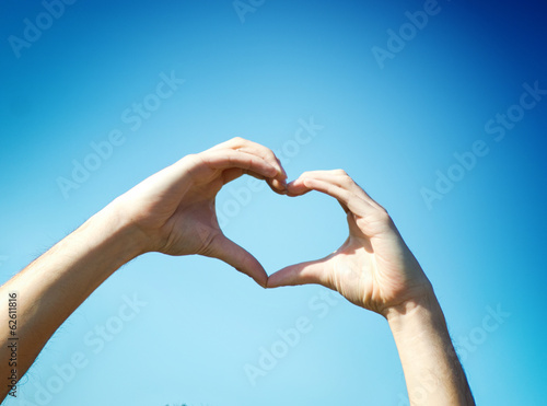 Photo: Hand heart shape against blue sky Hand heart shape against blue sky