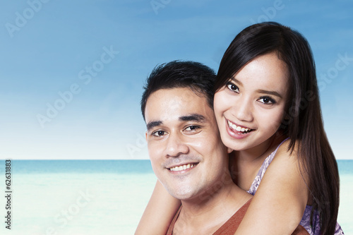 Photo: Young couple piggyback at beach Young couple piggyback at beach