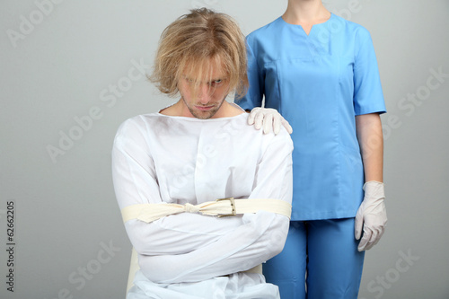 Photo: Mentally ill man in strait-jacket on gray background Mentally ill man in strait-jacket on gray background