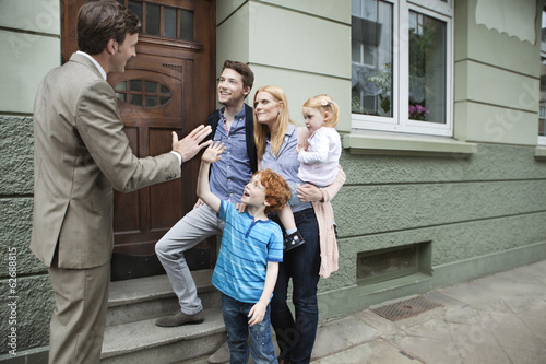 Photo: Deutschland, Düsseldorf, Junge, high Five, Immobilienmakler und Familie stehen im Hintergrund Deutschland, Düsseldorf, Junge, high Five, Immobilienmakler und Familie stehen im Hintergrund