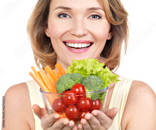 Photo: Portrait of a young smiling woman with a plate of vegetables. Portrait of a young smiling woman with a plate of vegetables.