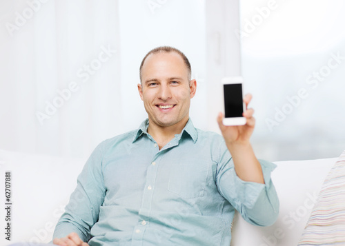 Photo: smiling man with smartphone at home smiling man with smartphone at home