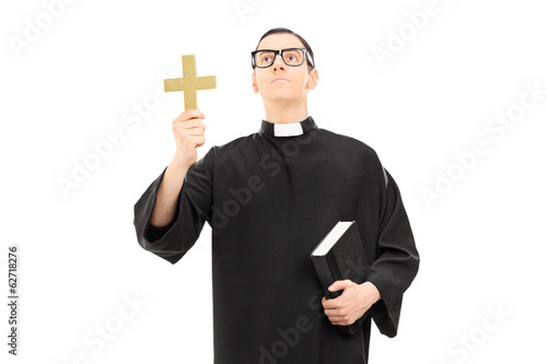 Photo: Priest holding a cross and looking up Priest holding a cross and looking up