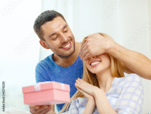 Photo: smiling man surprises his girlfriend with present smiling man surprises his girlfriend with present