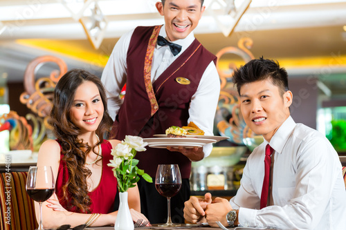 Photo: Chinese waiter serving dinner in elegant restaurant or Hotel Chinese waiter serving dinner in elegant restaurant or Hotel
