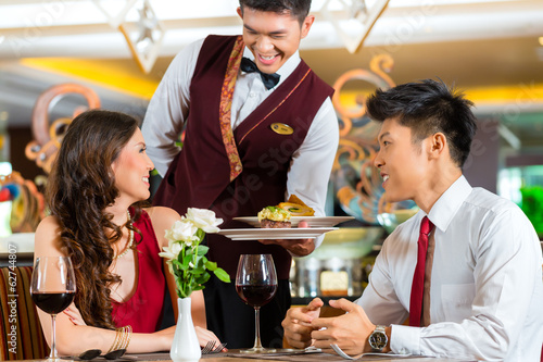 Photo: Chinese waiter serving dinner in elegant restaurant or Hotel Chinese waiter serving dinner in elegant restaurant or Hotel