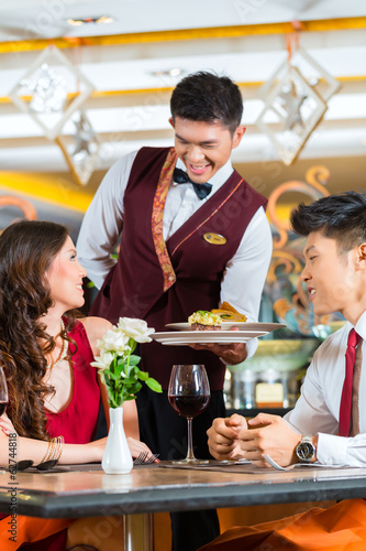 Photo: Chinese waiter serving dinner in elegant restaurant or Hotel Chinese waiter serving dinner in elegant restaurant or Hotel