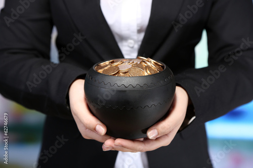 Photo: Ceramic pot with golden coins in female hands, Ceramic pot with golden coins in female hands,