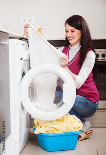 Photo: woman looking white clothes near washing machine woman looking white clothes near washing machine