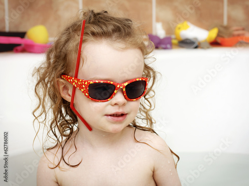 Photo: Little toddler playing in the bath with sunglasses Little toddler playing in the bath with sunglasses