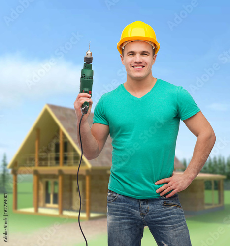 Photo: smiling manual worker in helmet with drill machine smiling manual worker in helmet with drill machine
