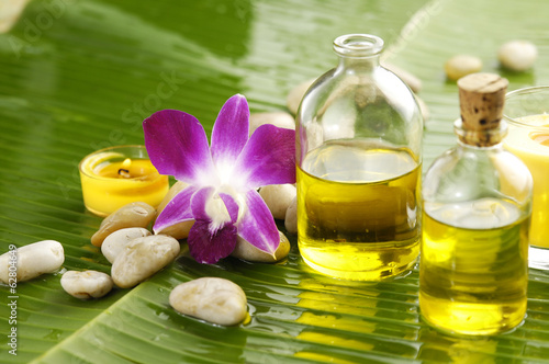Photo: Health spa with massage oil and pink orchid on leaf Health spa with massage oil and pink orchid on leaf