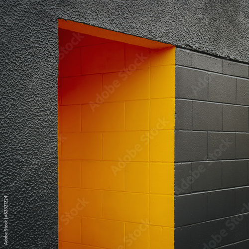 Photo: A doorway recess, painted orange in a grey block concrete wall. A doorway recess, painted orange in a grey block concrete wall.