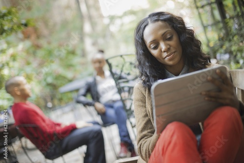 Foto: Scenes from urban life in New York City. Outdoors. Two people in background. A woman using a computer tablet or pad. Scenes from urban life in New York City. Outdoors. Two people in background. A woman using a computer tablet or pad.