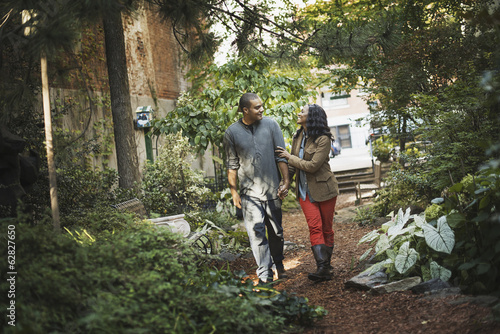 Foto: Scenes from urban life in New York City. A man and a woman, a couple walking through the park, through a leafy space, with trees and green foliage and a bench. Scenes from urban life in New York City. A man and a woman, a couple walking through the park, through a leafy space, with trees and green foliage and a bench.