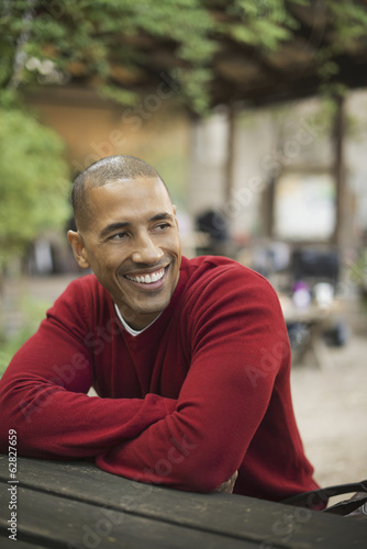 Foto: Scenes from urban life in New York City. A man in a red jumper seated at a bench, smiling. Scenes from urban life in New York City. A man in a red jumper seated at a bench, smiling.