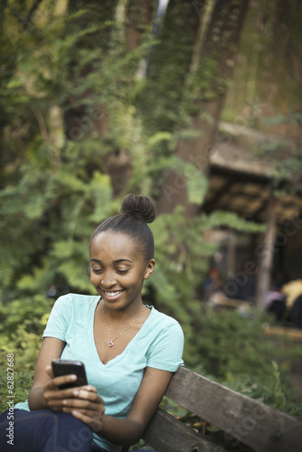 Foto: Scenes from urban life in New York City. A young teenage girl sitting on a bench, looking at a pad screen or texting. Scenes from urban life in New York City. A young teenage girl sitting on a bench, looking at a pad screen or texting.