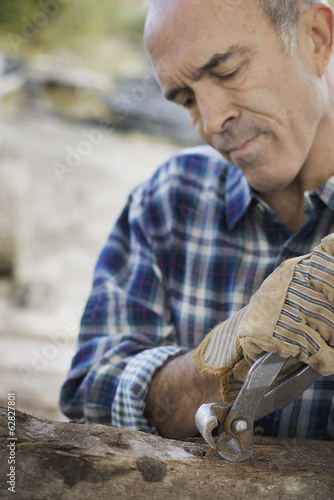 Foto: A reclaimed lumber workshop. A man preparing the timber by removing all the nails and studs. A reclaimed lumber workshop. A man preparing the timber by removing all the nails and studs.