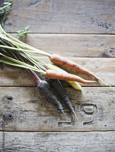 Photo: A domestic kitchen table with a worn scrubbed surface. A bunch of fresh carrots. A domestic kitchen table with a worn scrubbed surface. A bunch of fresh carrots.