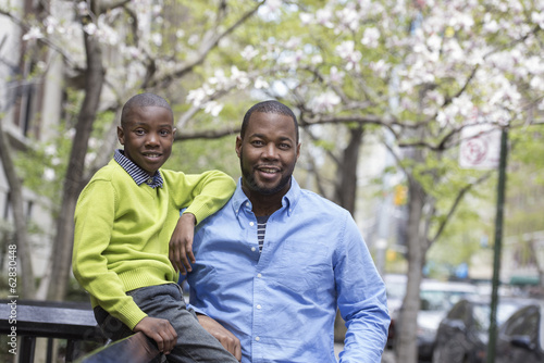 Foto: A New York city park in the spring. Sunshine and cherry blossom. A boy sitting on a fence, beside his father. A New York city park in the spring. Sunshine and cherry blossom. A boy sitting on a fence, beside his father.